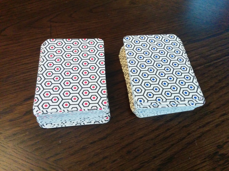 Photograph of two decks of cards with red and blue abstract backs.